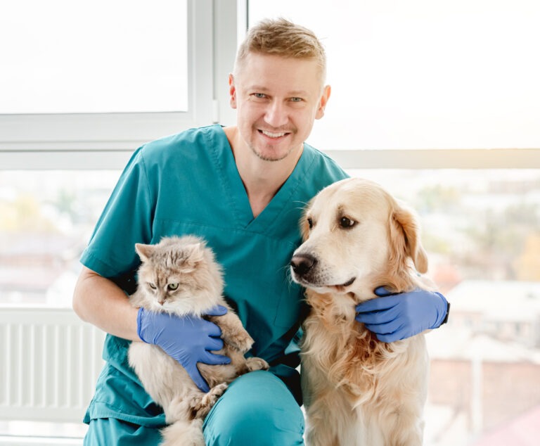 Happy veterinarian hugging dog and cat